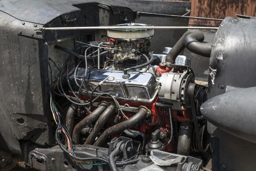 Old antique car engine on clean and pristine condition. Many wires, hoses, and chrome. 