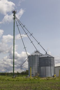 Huge modern metal silos and accompanying devices. Blue skies and clouds. 