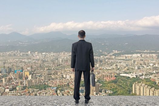 Asian business man stand and look the city under sky, concept of hard work, business, future etc.