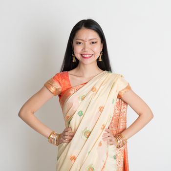 Portrait of confident Indian girl in sari smiling over grey background.