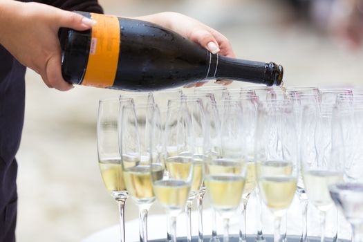 Banquet event. Waiter pouring champagne into glass. 