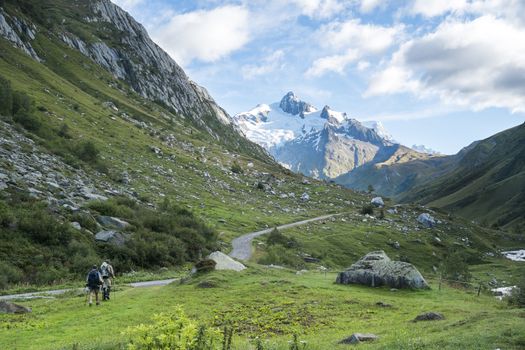 LES CHAPIEUX, FRANCE - AUGUST 27: Hikers walking with Glacier Needles in the background. The region is a stage at the Mont Blanc tour, which crosses three countries. August 27, 2014 in Les Chapieux.