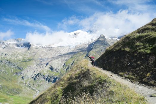 VILLE DES GLACIERS, FRANCE - AUGUST 27: Hiker walking towards Glacier Needles. The region is a stage at the Mont Blanc tour, which crosses three countries. August 27, 2014 in Ville des Glaciers.