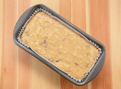 Raw banana loaf batter in a lined tin on a wooden table