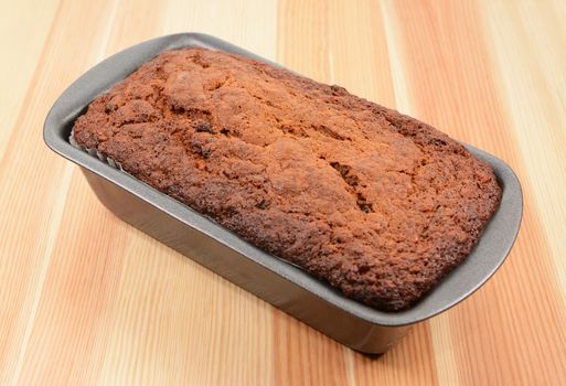 Freshly baked banana bread in a loaf tin on a pine table
