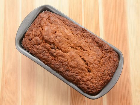 Freshly baked banana loaf in a lined tin on a wooden table