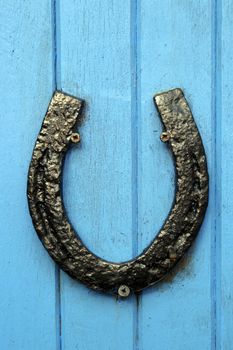 black horseshoe nailed to blue painted wooden boards on a door or wall