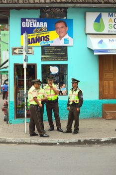 BANOS, ECUADOR - FEBRUARY 22, 2014: Unidentified policemen standing at the corner of the Pedro Vicente Maldonado Street at the bus station on February 22, 2014 in Banos, Ecuador.