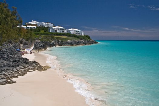 A tropical beach and headland, with a clear blue sea, on a summers day