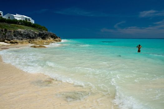 A tropical coastline with a lone girl in the ocean