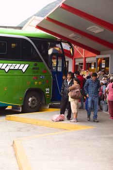 BANOS, ECUADOR - FEBRUARY 22, 2014: Unidentified people at the bus terminal with a bus standing in the back and snack stands on the side on February 22, 2014 in Banos, Ecuador. 