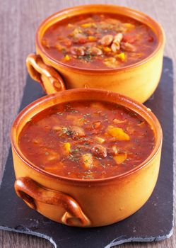 Soup in two crock pots, with beans, tomatoes and bread, vertical image