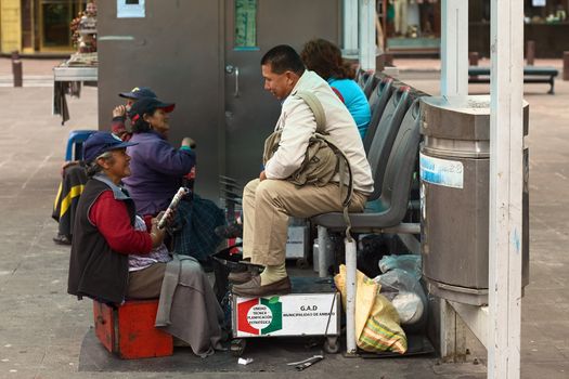 AMBATO, ECUADOR - JUNE 23, 2014: Unidentified female shoeblack talking to a customer in Cevallos Park in the city center on June 23, 2014 in Ambato, Ecuador. Ambato is the capital of Tungurahua Province in Central Ecuador. 