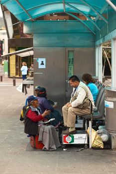 AMBATO, ECUADOR - JUNE 23, 2014: Unidentified female shoeblack talking to a customer in Cevallos Park in the city center on June 23, 2014 in Ambato, Ecuador. Ambato is the capital of Tungurahua Province in Central Ecuador. 