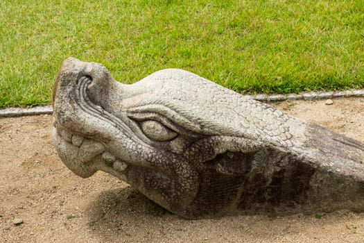 stone head of a monster sticking out of the ground