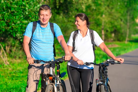 couple riding a bicycle in a park in the morning