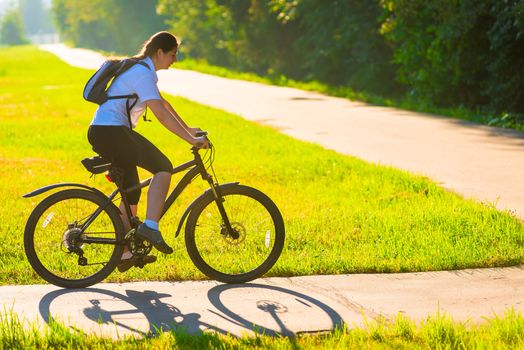 girl on bike rides on the bike path in the park