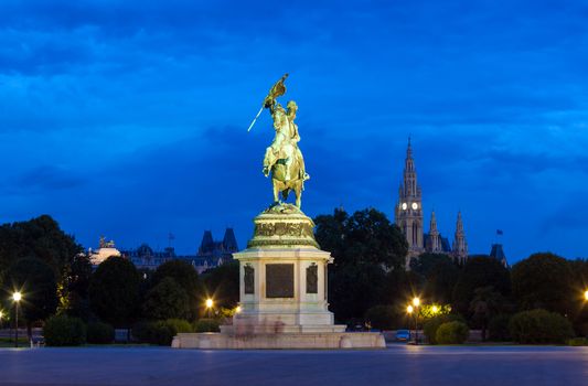VIENNA, AUSTRIA - AUGUST 4, 2013: Monument dedicated to Archduke Charles of Austria (Erzherzog Karl) ridding a horse and the city hall (Rathause) in Vienna, Austria.