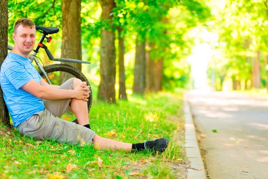 man resting against a tree with a bicycle