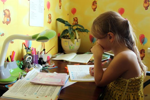 schoolgirl learns lessons at the table in her room