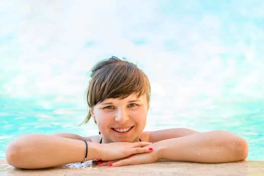 Portrait of a cheerful and beautiful girl in the pool water