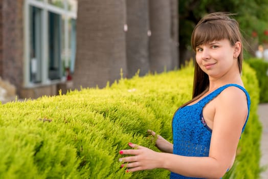 girl near a green bush is very young and beautiful