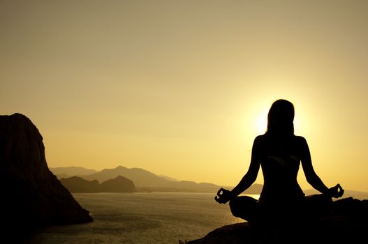 Yoga lotus position silhouette on seaside at sunrise