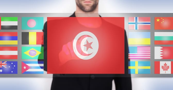 Hand pushing on a touch screen interface, choosing language or country, Tunisia