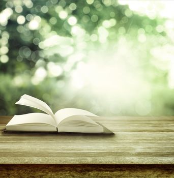 Open book on table in front of spring background