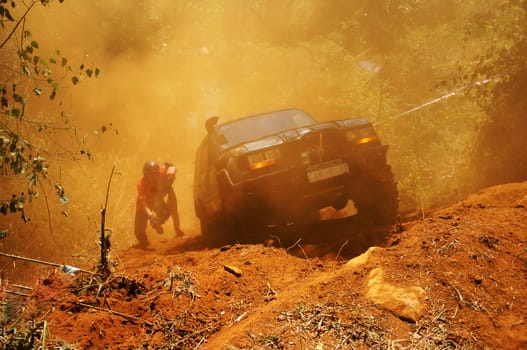 Racer at terrain racing car competition, the car try to cross extreme off road with red earth,  wheel make splash of soil and dusty air, competitor  adventure in championship spirit 