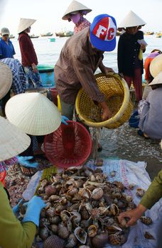 PHAN THIET- VIETNAM- JAN 21:  Seafood market on beach, people trader fishing product in morning, boat on water,  woman buy and sell fresh food, Viet Nam, Jan 21, 2014