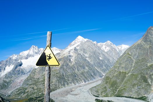 COMBAL, ITALY, AUGUST 28: Slippage danger sign with Miage Glacier and Combal peaks in the background. The area is on a stage of the popular European Mont Blanc tour. August 28, 2014 in Combal.