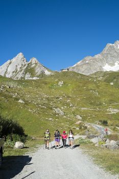 VAL VENY, ITALY - AUGUST 28: Hikers walking on dirt road with Elisabetta Soldini Refuge in the background. The refuge is on a stage of the popular Mont Blanc tour. August 28, 2014 in Val Veny.