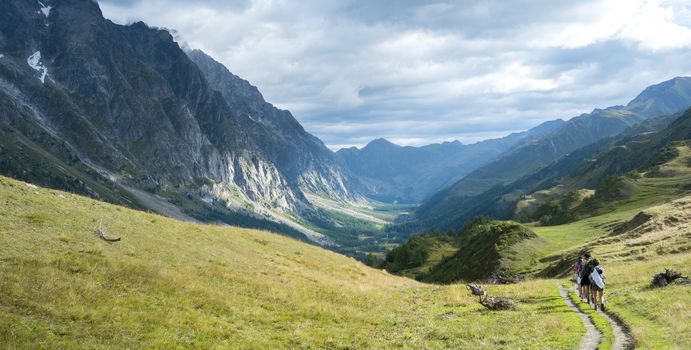 VAL FERRET, ITALY - AUGUST 29: Hikers walking in Val Ferret in Italy, with overcast sky and rocky mountain range. The area is a stage of the Mont Blanc tour. September 29, 2014 in Val Ferret.