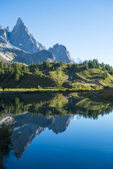 Combal Needles reflected on Combal Lake water on a sunny day in Val Veny, in Italy.