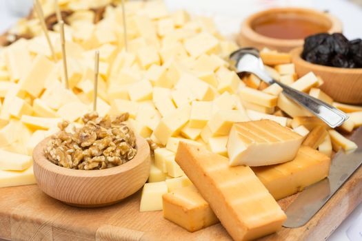 Cheese Plate with Dried Fruit, Nuts and Honey. Rustic decoration on a wooden plate.
