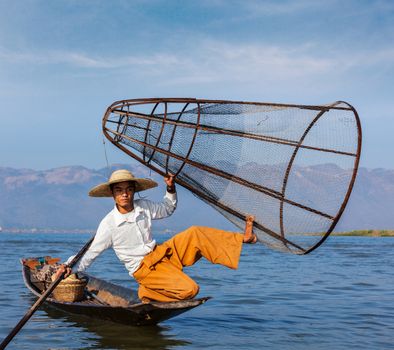 Myanmar travel attraction landmark - Traditional Burmese fisherman with fishing net at Inle lake in Myanmar famous for their distinctive one legged rowing style