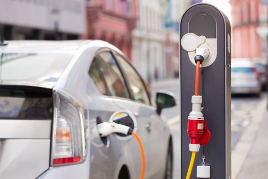 Power supply for electric car charging.  Electric car charging station. Close up of the power supply plugged into an electric car being charged.