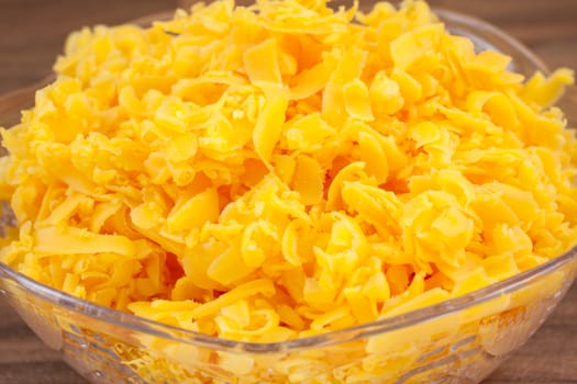 Shredded sharp cheddar cheese in a bowl on a counter top.