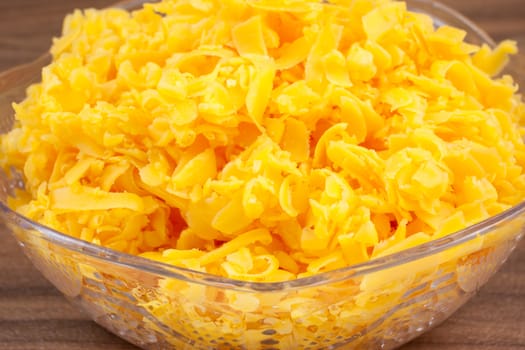 Shredded sharp cheddar cheese in a bowl on a counter top.