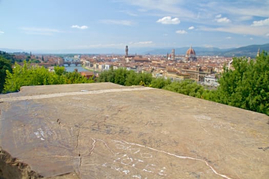 Photo shows a general view onto the city with its roofs, houses and trees.