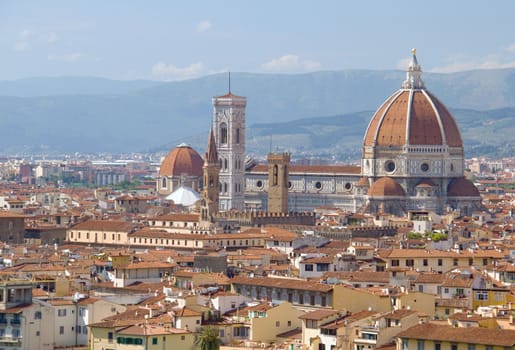 Photo shows a general view onto the city with its roofs, houses and trees.