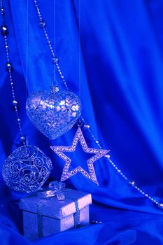 Silver christmas decoration and gift on blue fabric background