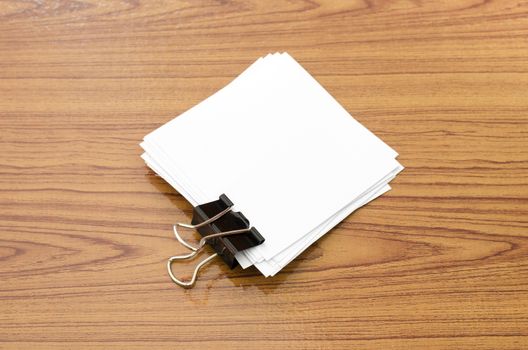 stack of paper with clip on wood background