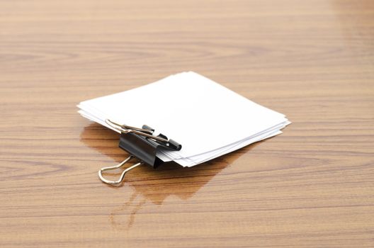 stack of paper with clip on wood background