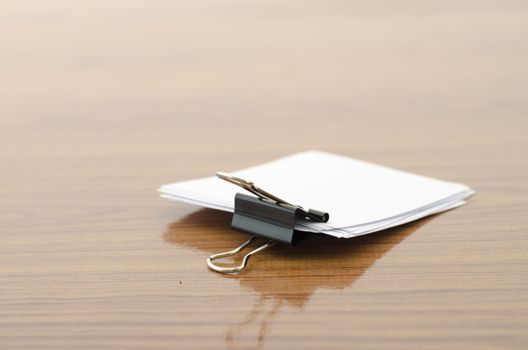 stack of paper with clip on wood background