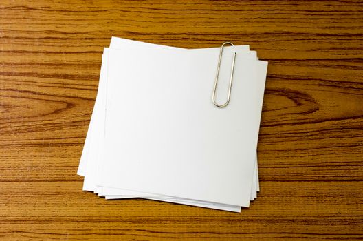 stack of paper with clip on wood background