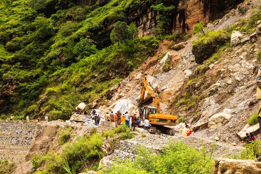 India - August 9 : The officers try to clear the big rock on highway from rishikech to joshimath after landslide due to heavy rain on August 9, 2014 in India