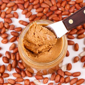 Peanut butter with heap of peanuts on the table