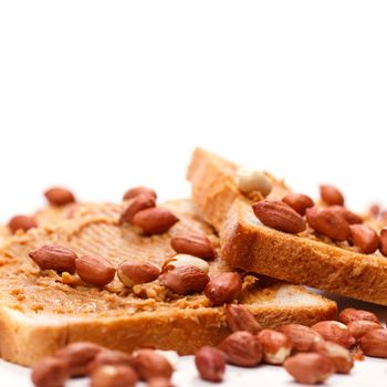 Peanut butter sandwich with heap of peanuts on the table